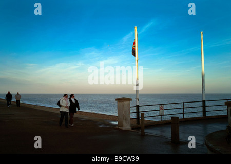 Les amis de prendre une promenade le long du front de mer à traiter Kent sur une froide soirée d'hiver Banque D'Images