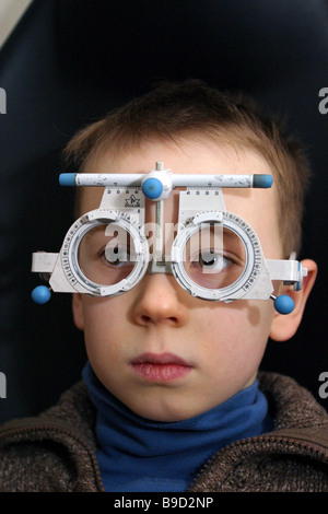 Jeune enfant ayant les yeux avec des lunettes optiques à l'essai Banque D'Images