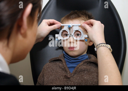 Jeune enfant ayant les yeux avec des lunettes optiques à l'essai Banque D'Images