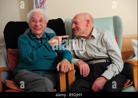 Un couple de personnes âgées assis en riant et heureux dans une maison de soins infirmiers. Banque D'Images
