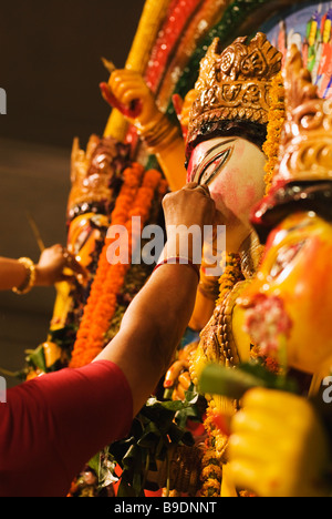 Les femmes appliquant tilak sur la statue de la déesse Durga, Kolkata, West Bengal, India Banque D'Images