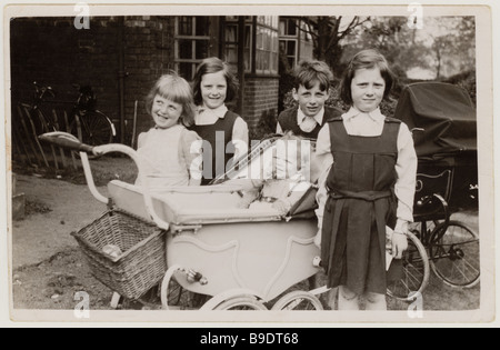 Les jeunes enfants de l'école qui ont des landaus s'occuper d'un bébé à l'extérieur de leur maison dans les années 1950, au Royaume-Uni Banque D'Images