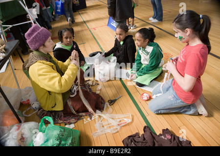 Femme d'enseigner aux enfants comment le crochet à l'aide de plastique recyclable à un salon vert à Syracuse New York Banque D'Images