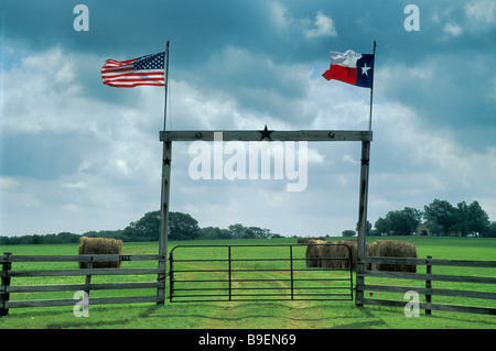 Ranch bois gate avec TX et drapeaux américains sur TX 90 l'autoroute près de Anderson Grimes County Texas USA Banque D'Images
