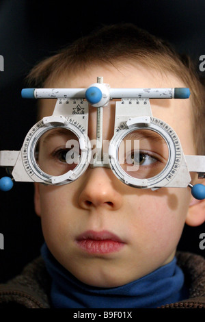 Jeune enfant ayant les yeux avec des lunettes optiques à l'essai Banque D'Images