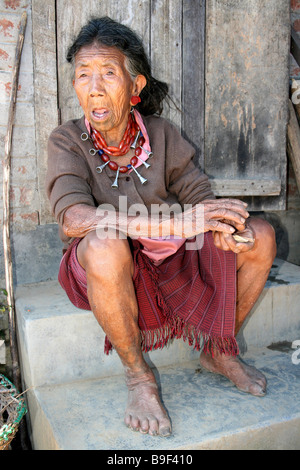 Ao ancienne tribu Naga Woman et des bouchons d'oreille assis dehors Hut Banque D'Images