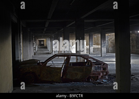 Une voiture abandonnée sur le parking souterrain d'une télévision conseil (France). Carcasse de voiture calcinée dans un sous-sol Banque D'Images