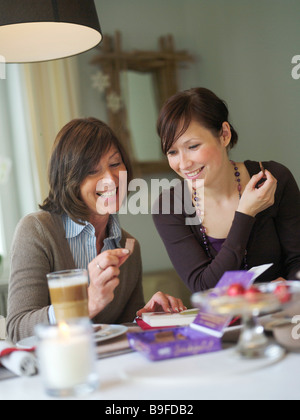 Femme montrant cookie pour sa fille à la table du petit déjeuner Banque D'Images