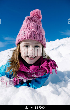 Portrait of Girl lying on snow and smiling Banque D'Images