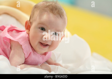 Bébé couché sur le ventre tête ascenseurs smiling portrait 4 mois éveil bébé repose sur le ventre d'observation de l'appareil photo un regard Banque D'Images