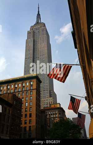 À la recherche jusqu'à l'Empire State Building, New York avec des drapeaux américains au premier plan encadrée par un ciel d'été. Banque D'Images
