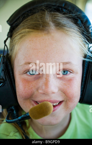 Jeune FRANÇAISE SMILING DU POSTE DE PILOTAGE D'UN AÉRONEF PORTANT UN CASQUE PILOTE Banque D'Images