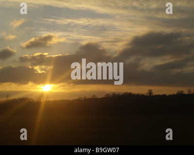 Coucher de soleil sur les champs de Buckinghamshire, où le soleil est bas dans le ciel en dessous de la ligne nuageuse Banque D'Images