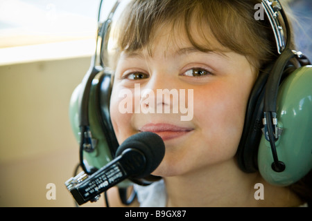 Jeune FRANÇAISE SMILING DU POSTE DE PILOTAGE D'UN AÉRONEF PORTANT UN CASQUE PILOTE Banque D'Images