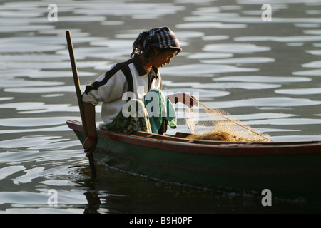 Une femme népalaise de poissons net son bateau sur le Lac Phewa à Pokhara, au Népal. Banque D'Images