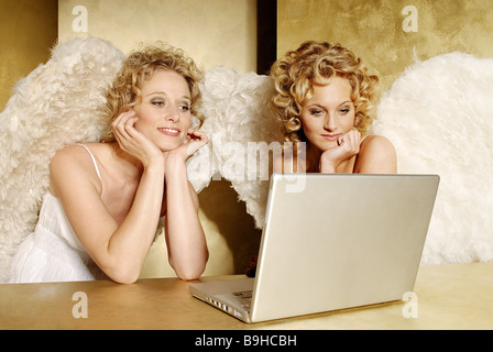 Jeune femme blonde d'ailes d'ange souriant gaiement rêves loin perdue dans ses pensées table ordinateur portable semi-portrait des gens de Noël Banque D'Images