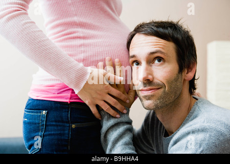 L'écoute de l'homme à femme est enceinte estomac Banque D'Images