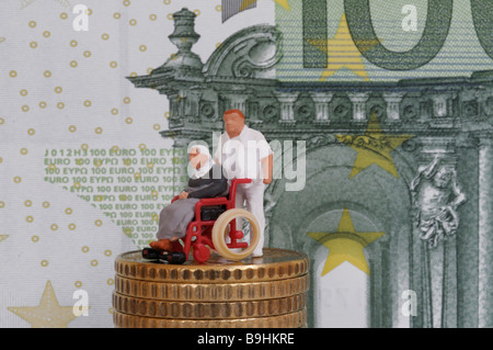 Infirmier en poussant une vieille personne en fauteuil roulant, figure sur une pile de pièces en face d'un projet de loi, 100 EUR pour une photo symbolique Banque D'Images