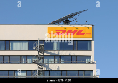 DHL logo sur un immeuble de bureaux, au-dessus de lui un module solaire mobile, construit sur des escaliers d'incendie Banque D'Images