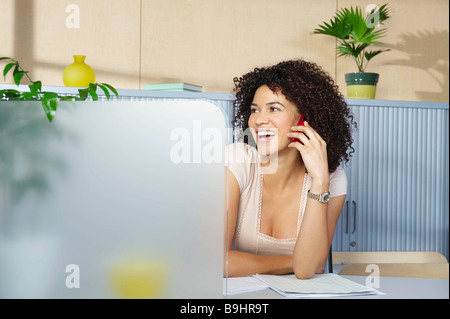 Young woman on phone at desk in office Banque D'Images