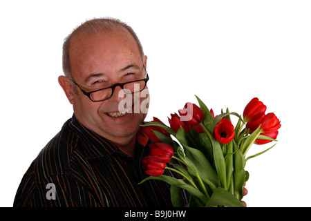 Pensionné rire portant des lunettes et en maintenant les tulipes Banque D'Images