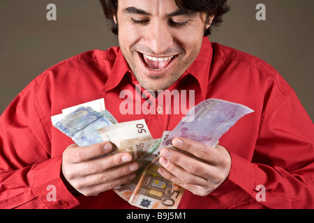 Jeune homme heureux au sujet de ses billets en euros Banque D'Images