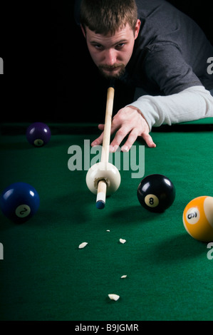 Un pool shark touchera un queue à travers une boule de choc Banque D'Images