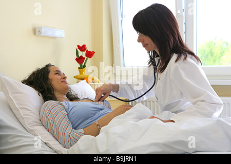 L'examen du médecin de l'hôpital femme enceinte de 20 à 30 ans 30 à 40 ans Profession Médecin lit soins livraison de la pression artérielle Banque D'Images