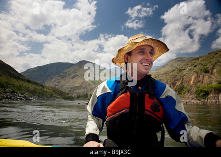 A smiling man flotte sur un radeau sur une rivière dans l'Idaho, aux États-Unis. Banque D'Images