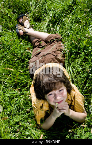 Portrait of young boy lying in grass Banque D'Images