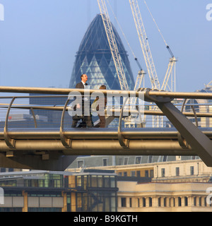 Un homme d'affaires de la ville traverse le pont du Millenium de Londres dans la ville de London uk Banque D'Images