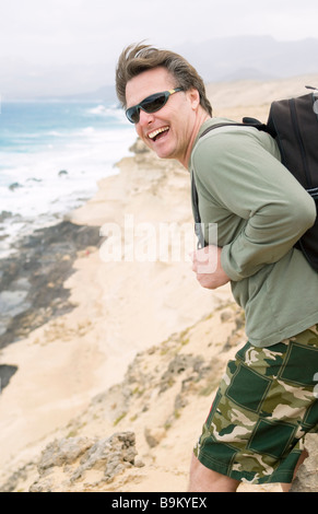 Une happy smiling quarantaine homme portant un sac à dos s'amuse sur son voyage de randonnée à Fuerteventura. Banque D'Images