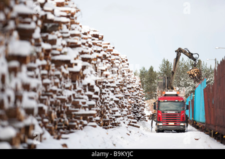 Chargement des grumes du camion à bord du train de grumes de fret à Winter au dépôt ferroviaire , Finlande Banque D'Images