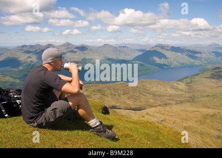 C'est un randonneur à prendre dans la magnifique vue depuis le sommet du Ben Lomond par une belle journée ensoleillée, Stirlingshire, Scotland Banque D'Images