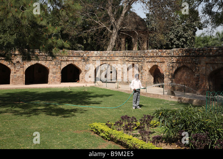 Un jardinier arrose les pelouses et d'arbres dans un jardin à la complexe Qutb Minar au sud de Delhi, Inde Banque D'Images