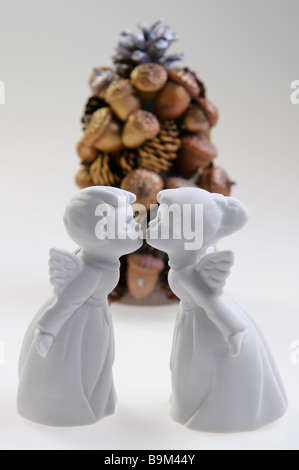 Porcelaine blanc garçon et fille anges s'embrasser devant un écrou borgne et arbre de Noël sur fond blanc Banque D'Images