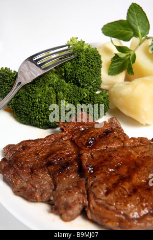 Ribeye Steak grillé servi avec brocoli et pommes de terre surmontée d'une feuille de menthe. Banque D'Images