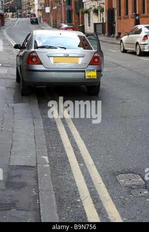 Voiture garée sur une double ligne jaune pas de zone de stationnement dans le centre-ville de Manchester UK Banque D'Images