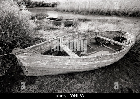 Vieux bateaux inutilisés se trouvant à marée basse, les marais salants de la côte nord du comté de Norfolk [Royaume-Uni]. Banque D'Images