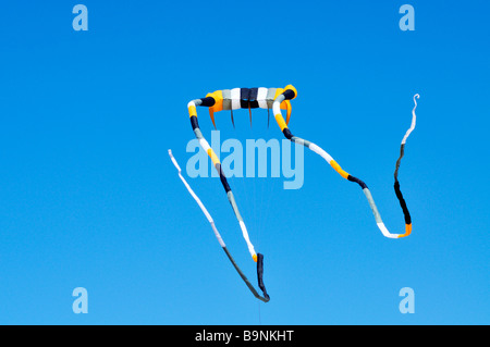 Un très grand cerf-volant avec de longues banderoles voler contre [ciel bleu clair] Banque D'Images