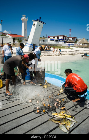 Yucatan Mexique Puerto Morelos 2009 les pêcheurs utilisent des filets pour attraper les poissons de récif avec de célèbres anciens et les nouveaux phares en arrière-plan Banque D'Images