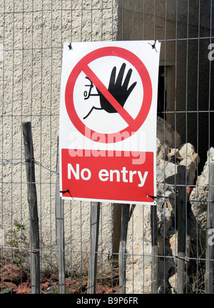 Panneau d'avertissement attaché à l'escrime à l'extérieur d'un bâtiment abandonné brûlé. Il lit '' pas d'entrée Banque D'Images