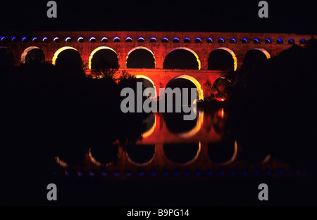 Vue de nuit de l'Aqueduc Romain, le Pont du Gard (c1stBC) éclairé la nuit et reflétée dans le Gard, près de Nimes, France Banque D'Images