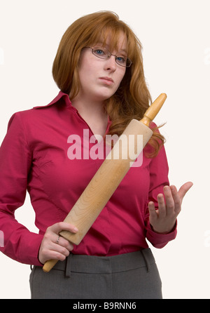 Une femme rousse en colère avec un rouleau à pâtisserie en bois spéléologie dans une manière menaçante. Banque D'Images