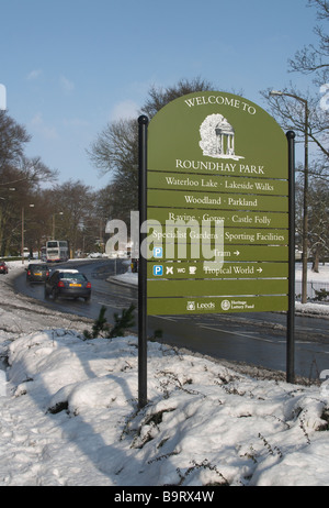 Scène de neige avec des arbres et arbustes et haies route qui traverse avec Bienvenue à Roundhay Park sign Banque D'Images