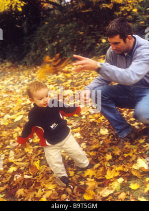 Le père avec son fils jouant avec les feuilles d'automne Banque D'Images