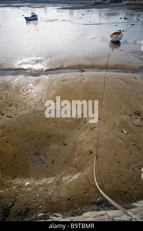 Bateaux à marée basse. Bateaux échoués dans la vase du port, l'une liée au quai par une longue chaîne. Banque D'Images