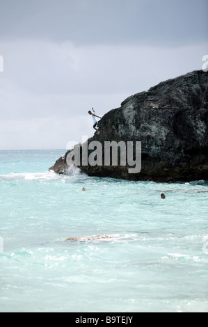 Young man jumping bermudien $d'une falaise dans la mer sur la plage de Stonehole (désactivation) Banque D'Images