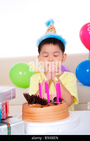 Boy making tiens en face de gâteau d'anniversaire Banque D'Images