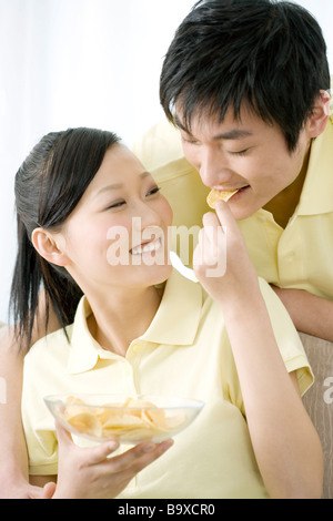 Jeune femme homme alimentation potato chip smiling Banque D'Images